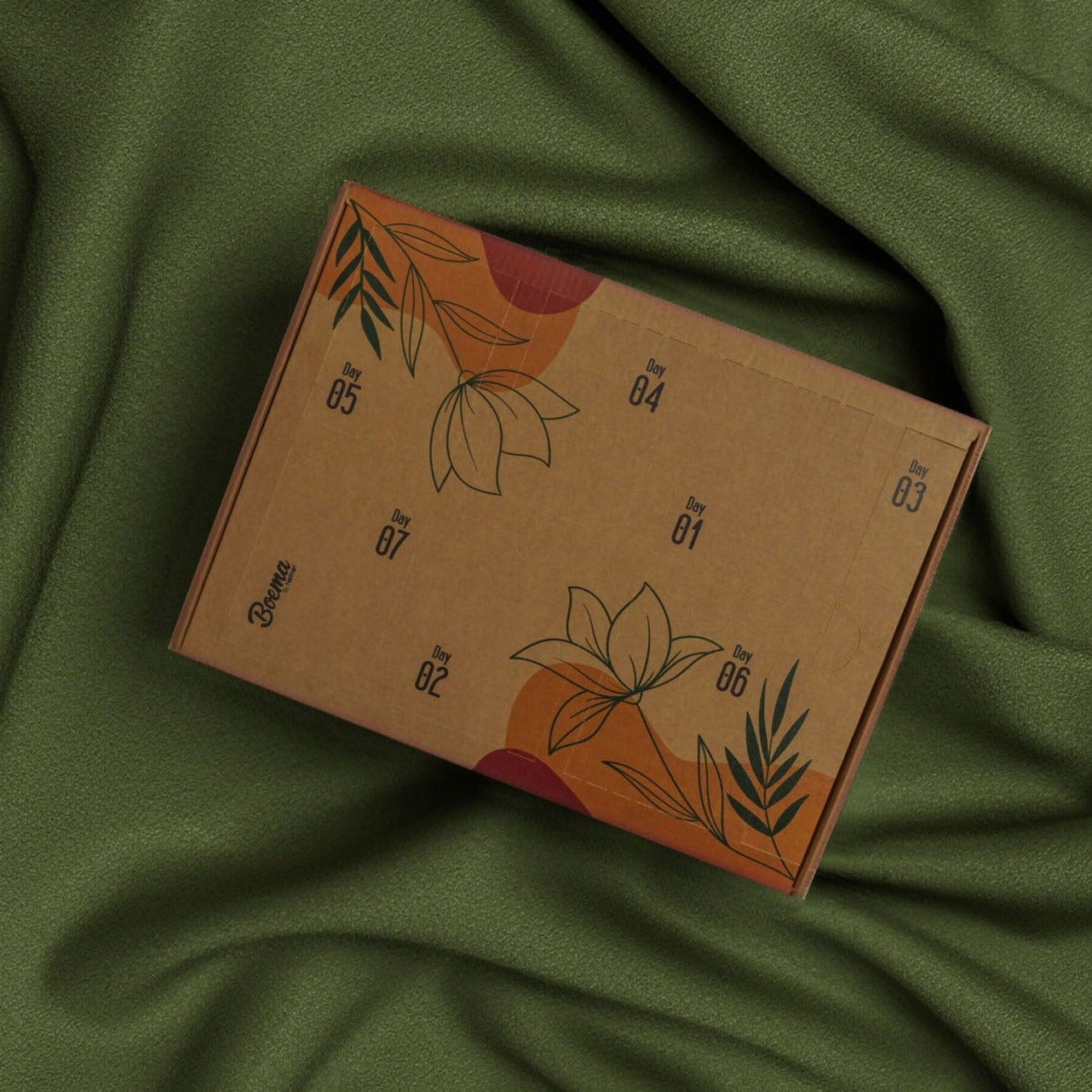 Brown cardboard box with floral designs on a green fabric background