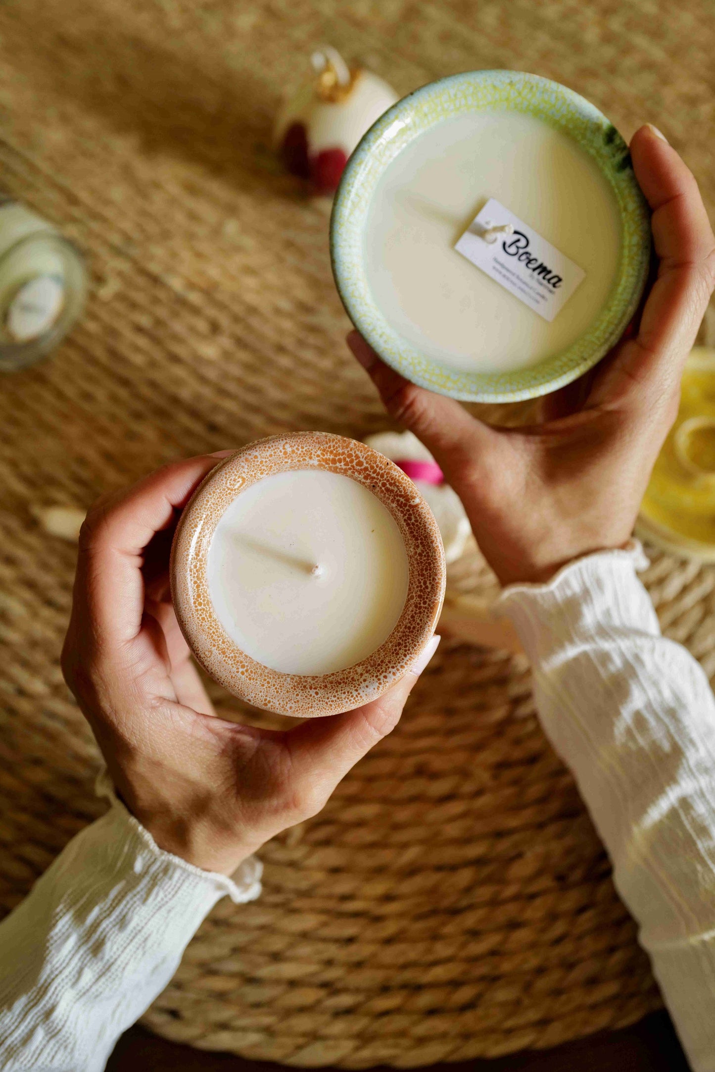 Two hands holding candles in pottery