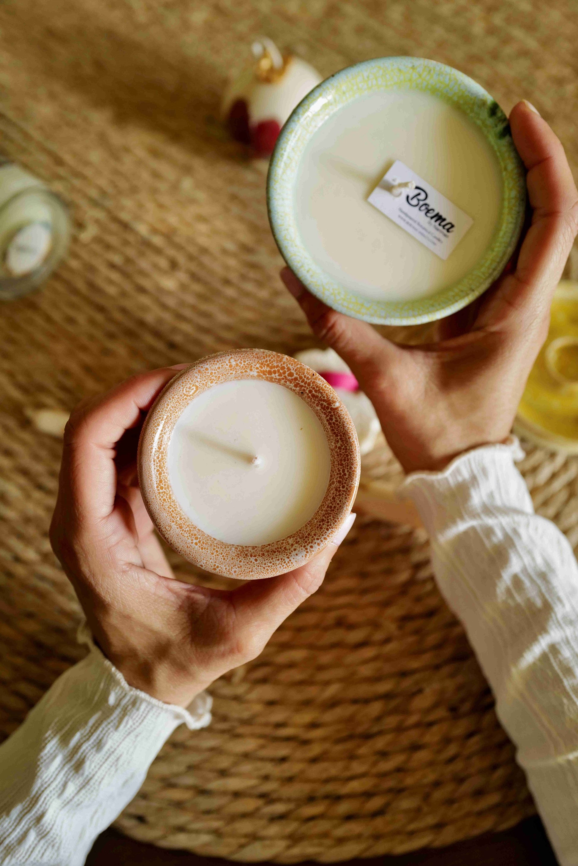 Two hands holding candles in pottery