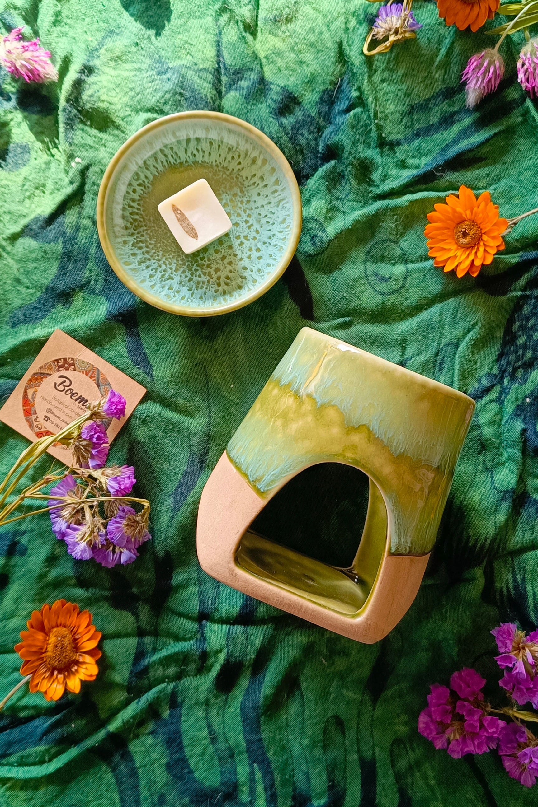 Ceramic oil burner with a soy or wax melt on a green fabric background with flowers